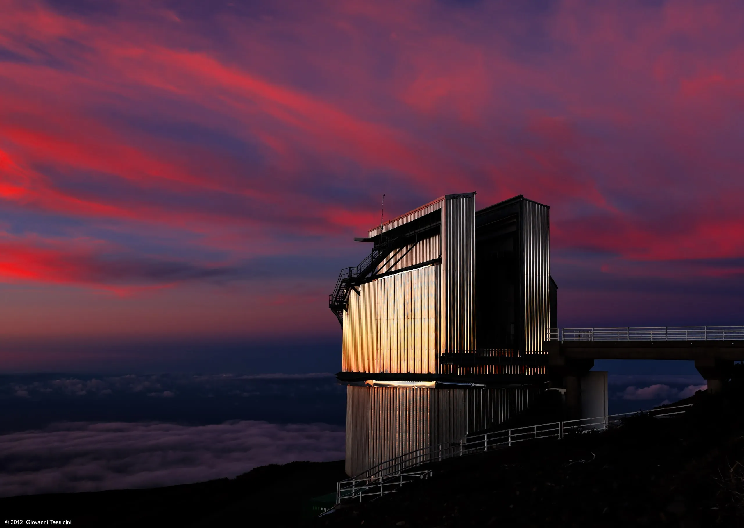 A telescope building on La Palma at dusk under red and purple clouds.
